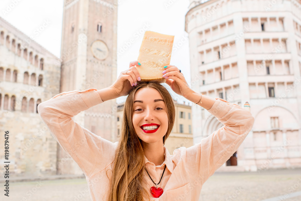 意大利帕尔马镇主广场上，一名年轻女子拿着一块帕尔马干酪。帕尔马干酪i