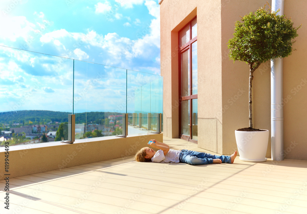 young boy relaxing on terrace, on top floor