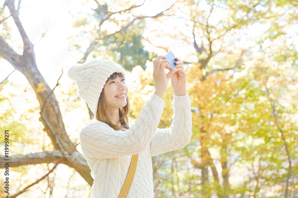 紅葉をスマートフォンで撮る女性