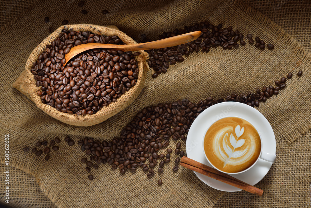 粗麻布背景下的一杯拿铁咖啡和咖啡豆俯视图