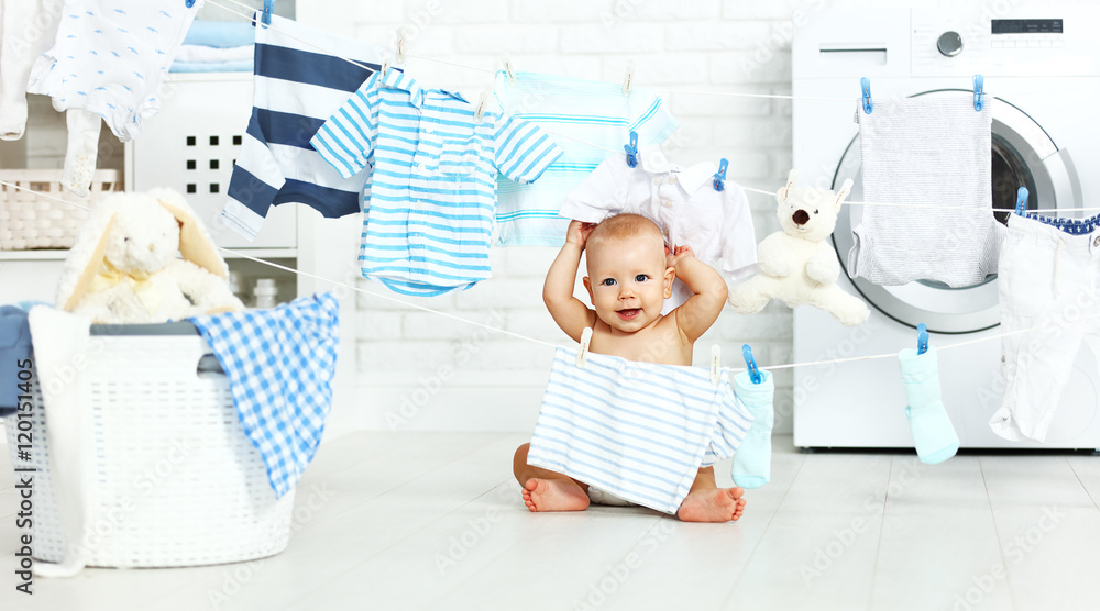 有趣快乐的男婴洗衣服，在洗衣房里开怀大笑