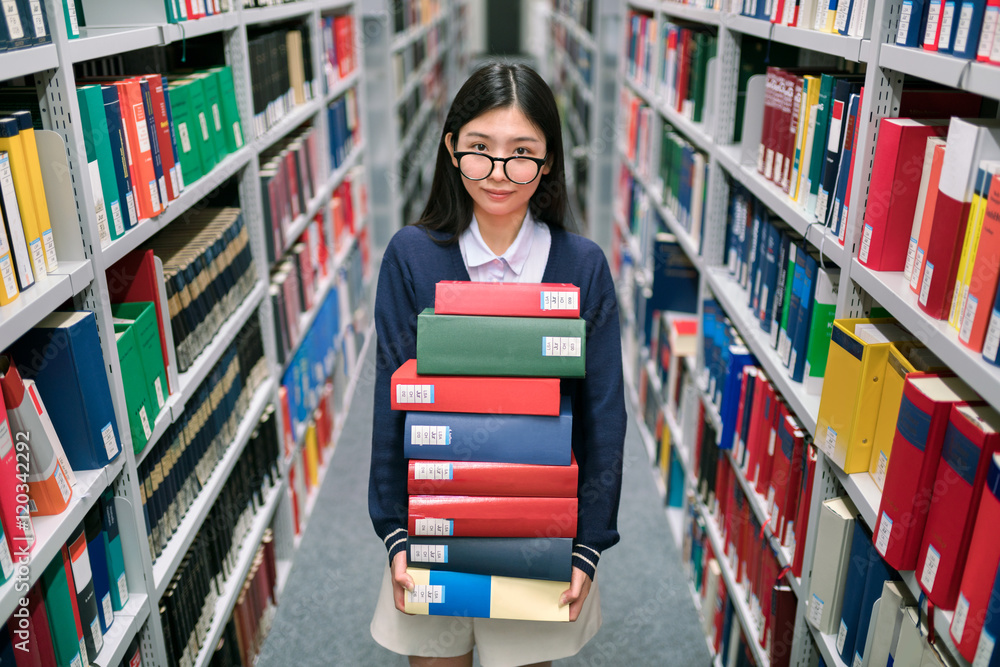 Junge Studentin mit einem Stapel Bücher