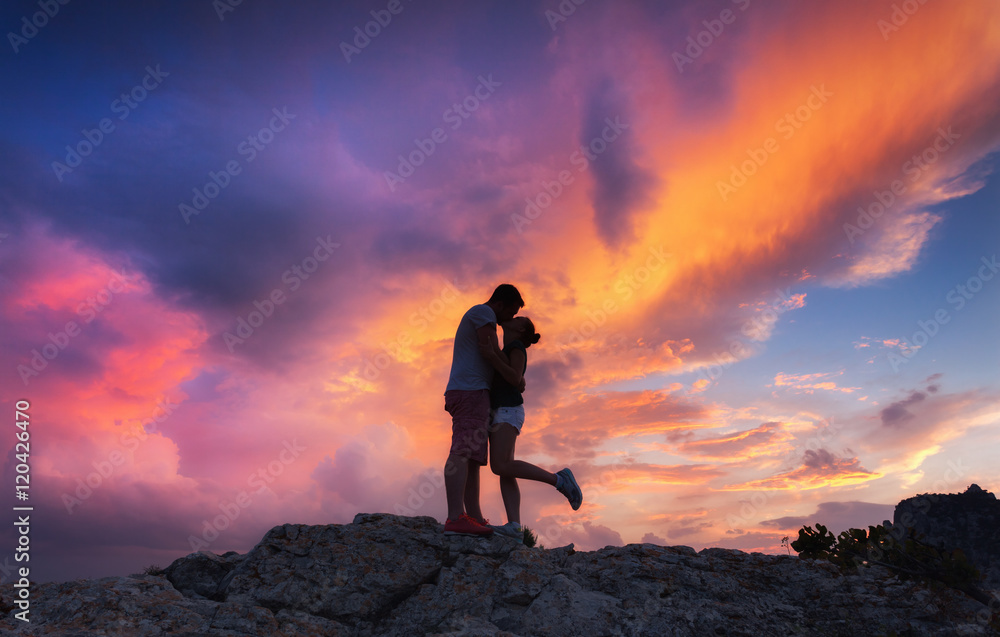 彩色山峰上一对男女拥抱亲吻的剪影