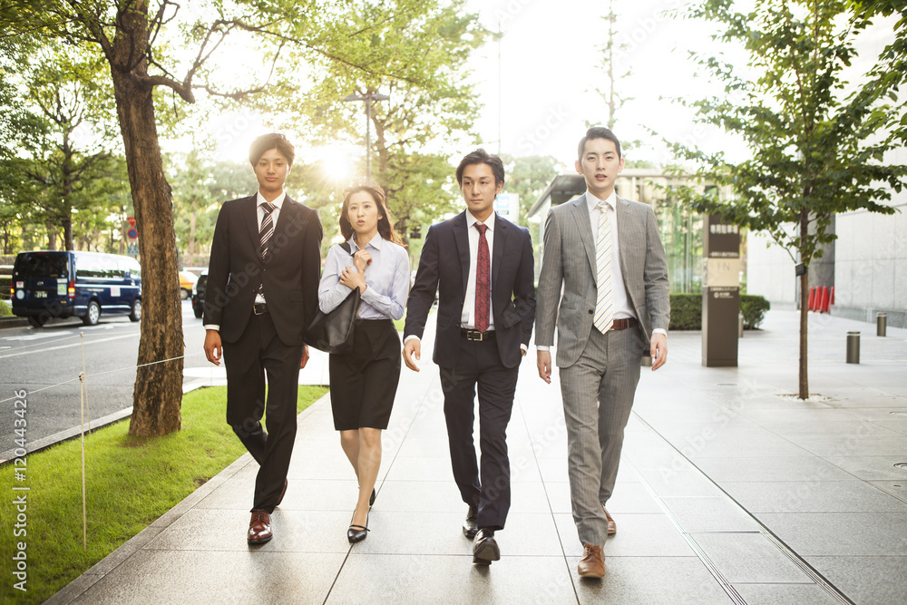 Four of the young business man is walking in the business district