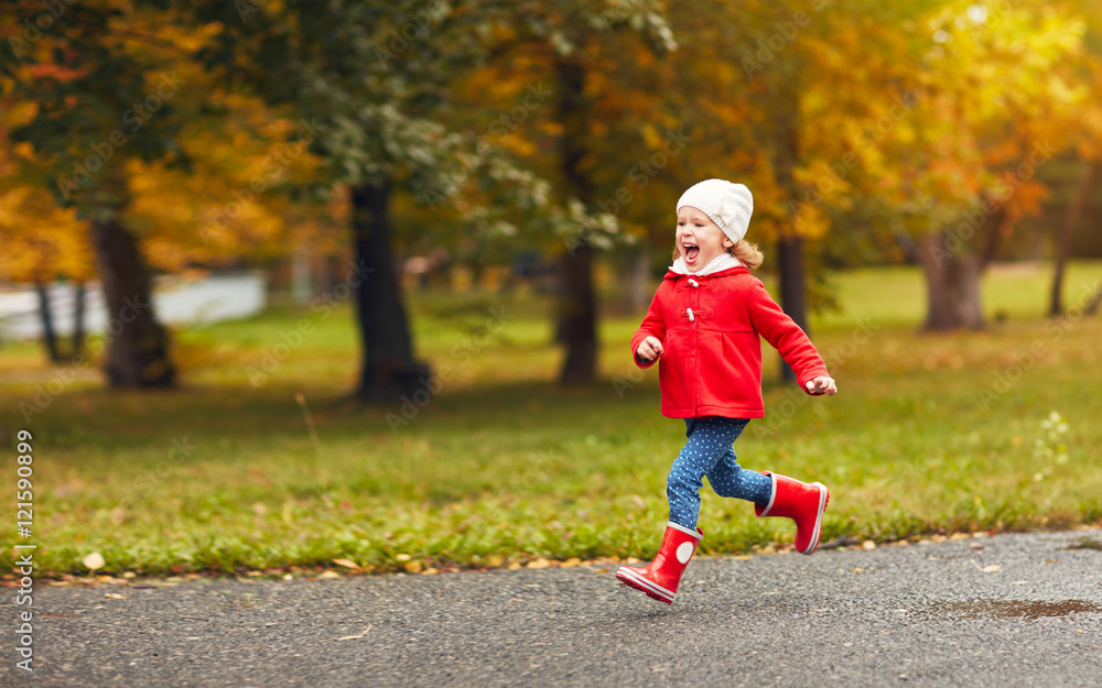 happy child girl running in nature in autumn after rain