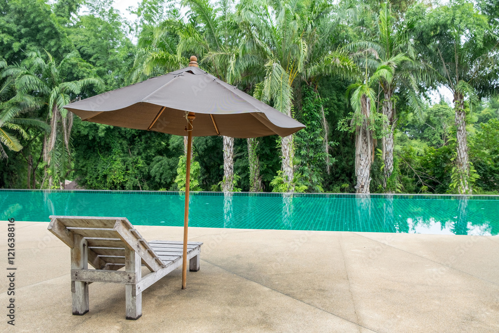 阴凉花园现代游泳池旁带伞的木制日光浴床