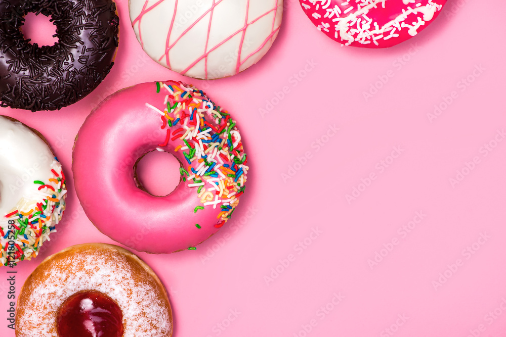 粉粉色背景上有糖霜的甜甜圈。甜甜甜圈。
