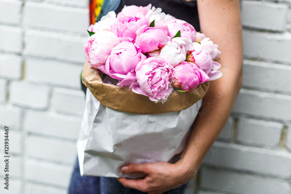 woman with bouquet of pink peonies in kraft paper