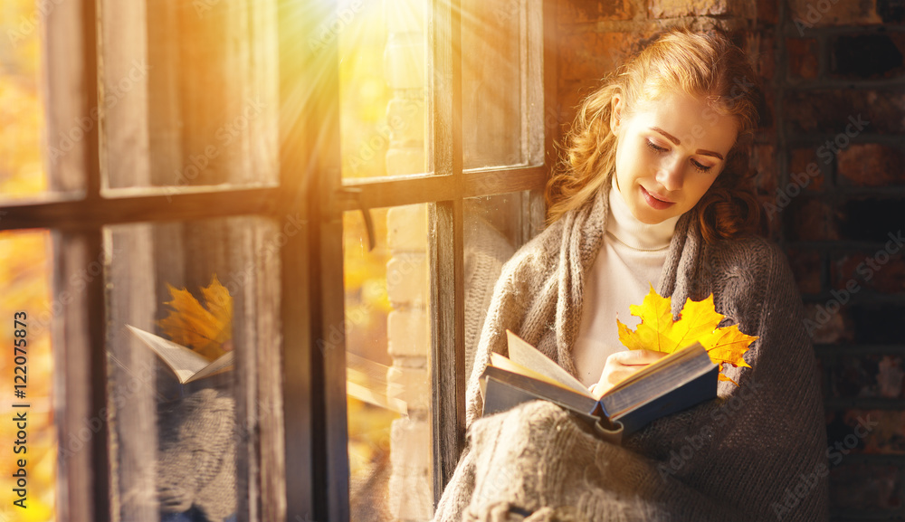 快乐的年轻女子在秋天靠窗读书