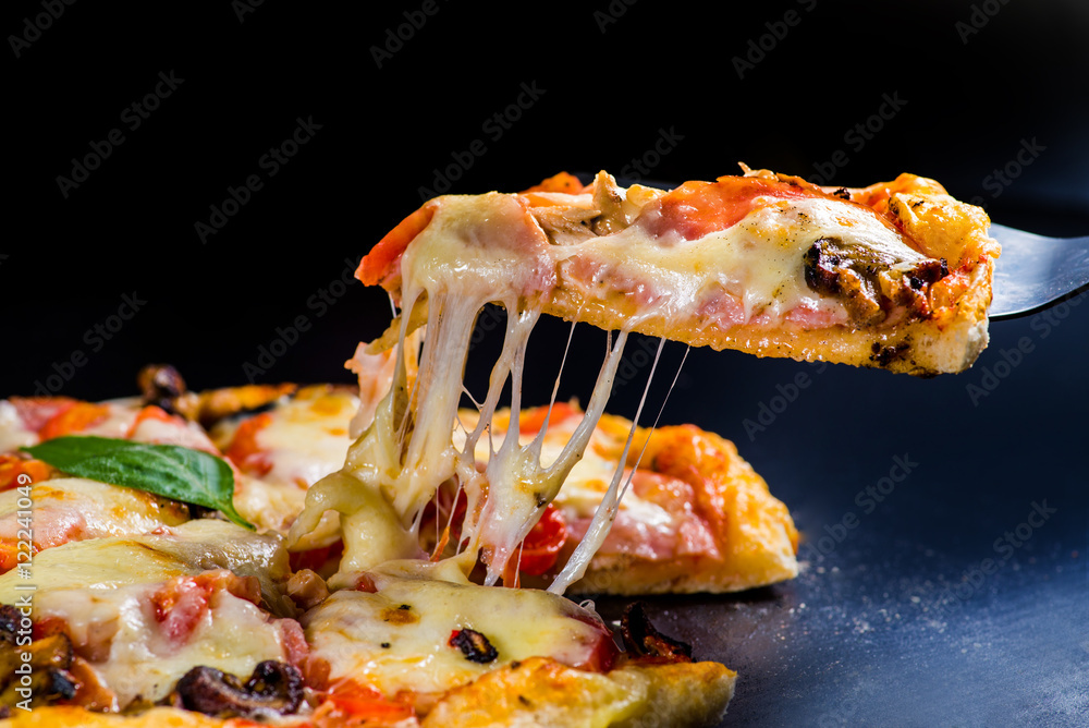 切下一片披萨。融化的奶酪从披萨上伸出来