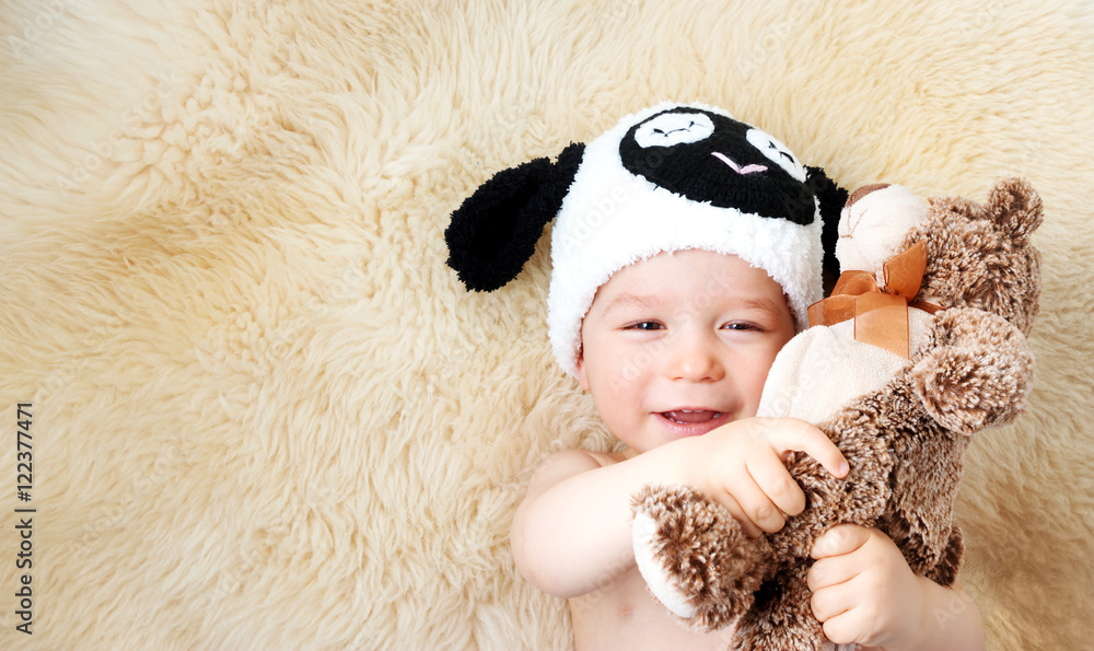 一岁婴儿戴着羊帽子躺在羊毛上