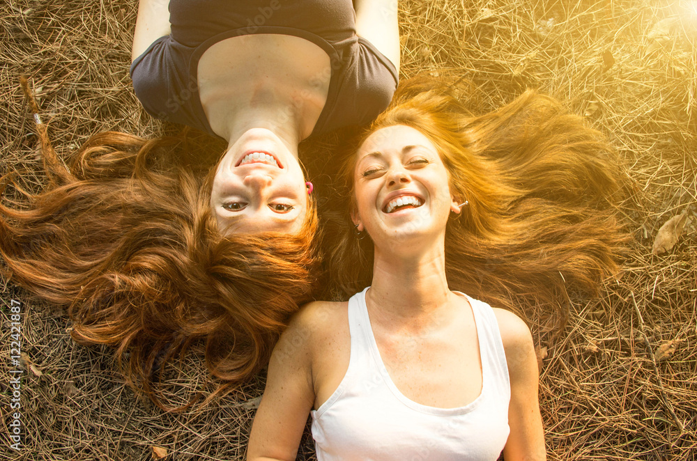 两个年轻女孩躺在草地上玩得很开心。