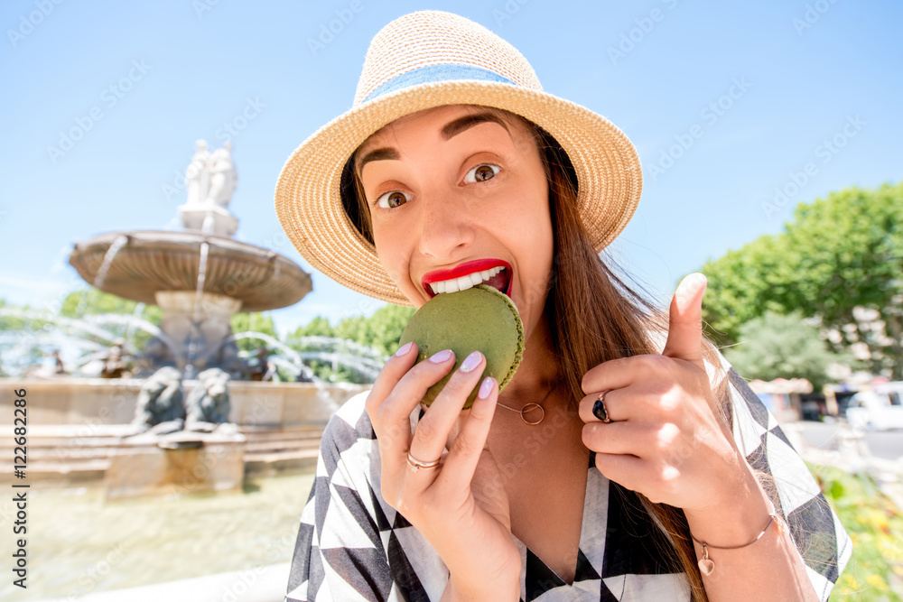 Young female tourist with macaron cookie near the famous fontain de la Rotonde in Aix-en-Provence in
