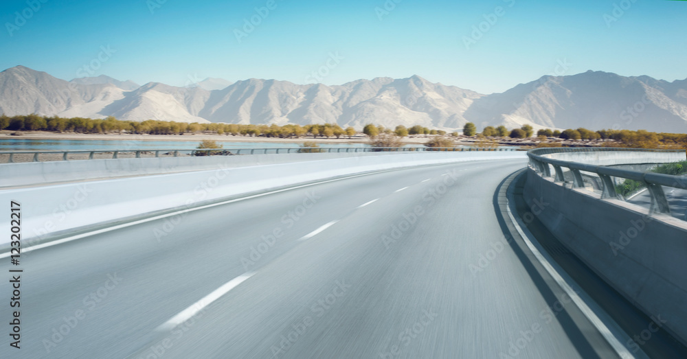 高速公路立交桥运动模糊，背景为山脉。