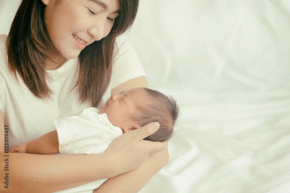 快乐的亚洲妈妈抱着可爱的小男孩。颜色柔和，