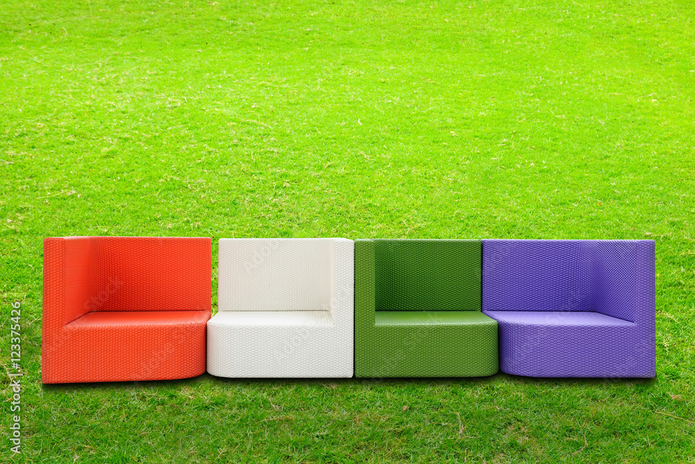 绿色庭院旁的彩色人造藤条沙发