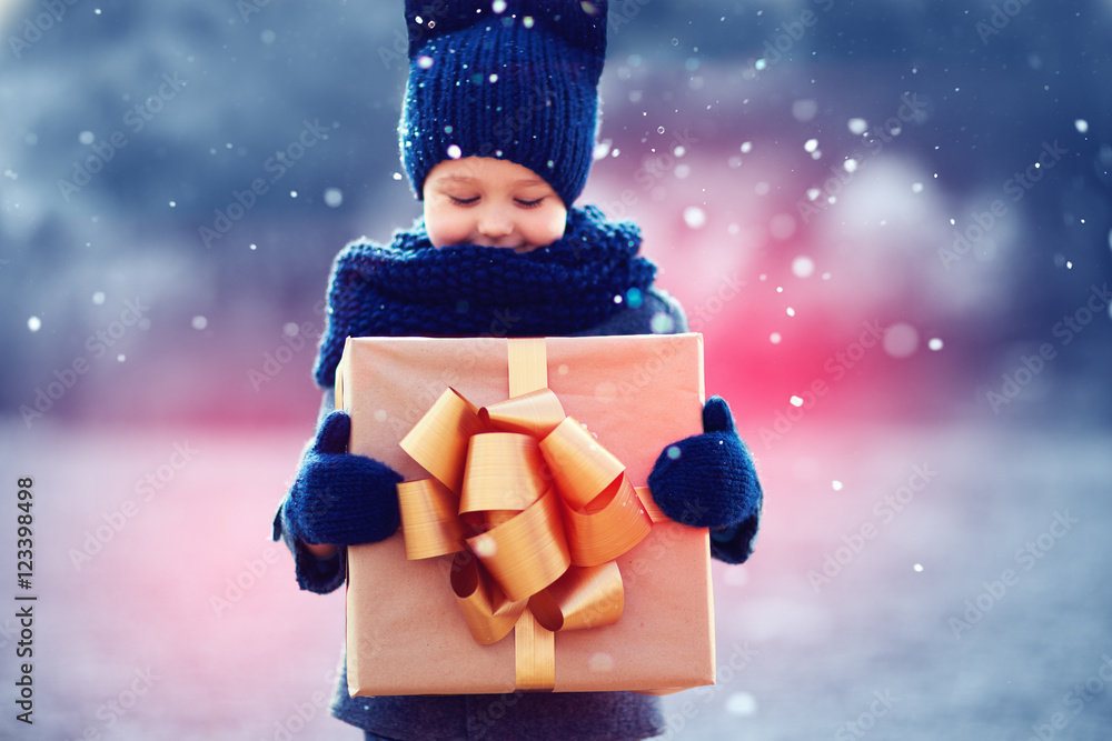 雪下可爱的孩子带着大礼盒。专注于礼盒