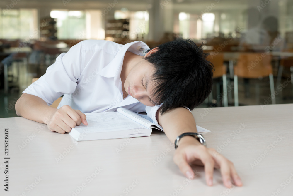 疲惫的亚洲学生或有书睡觉的亚洲年轻人