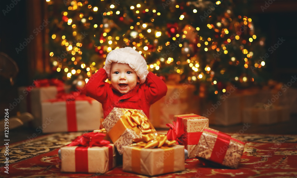 带礼物的圣诞树旁的快乐宝宝