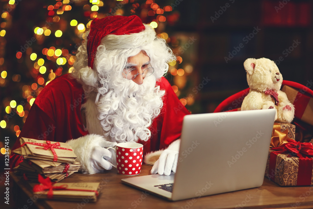 圣诞节。圣诞老人带着笔记本电脑阅读信件