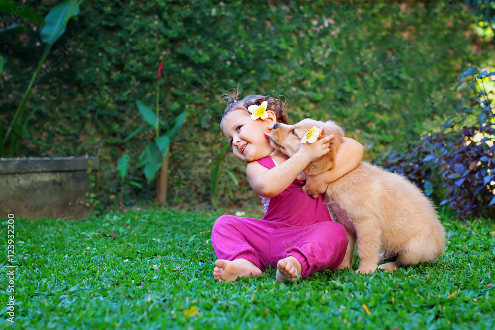 快乐的婴儿拥抱美丽的金色拉布拉多寻回犬的有趣照片。女孩和狗玩耍。Fam