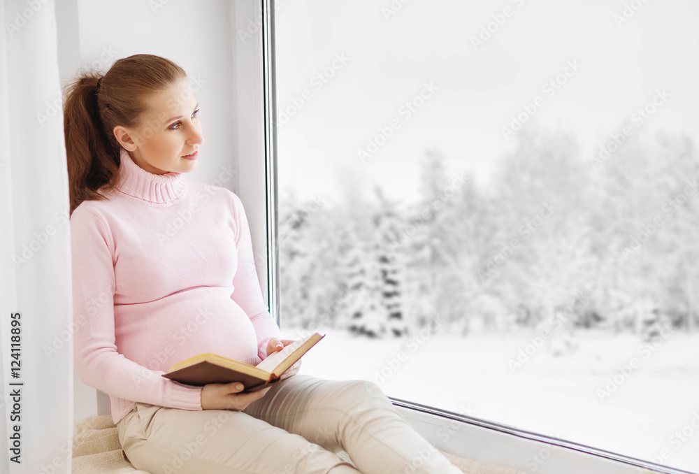 快乐的孕妇坐在窗户边看书
