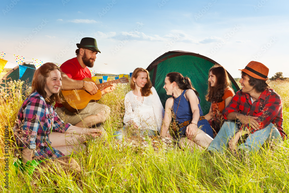 年轻人在露营地对着吉他唱歌