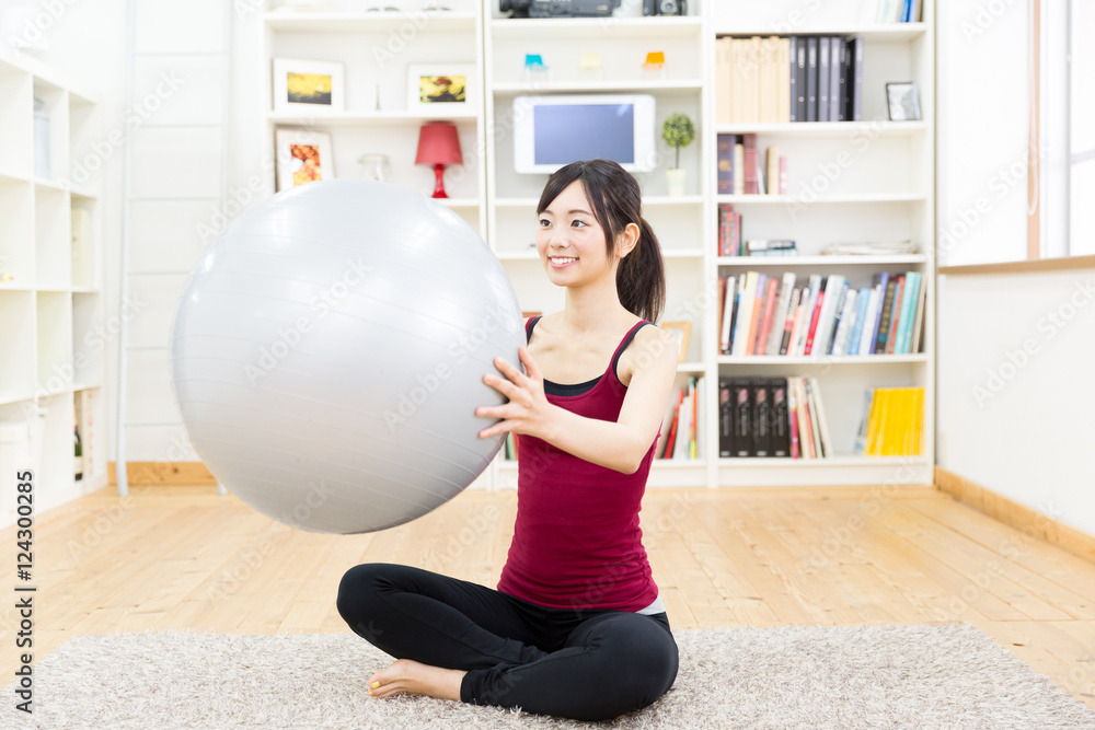 运动型亚洲女性在客厅使用平衡球