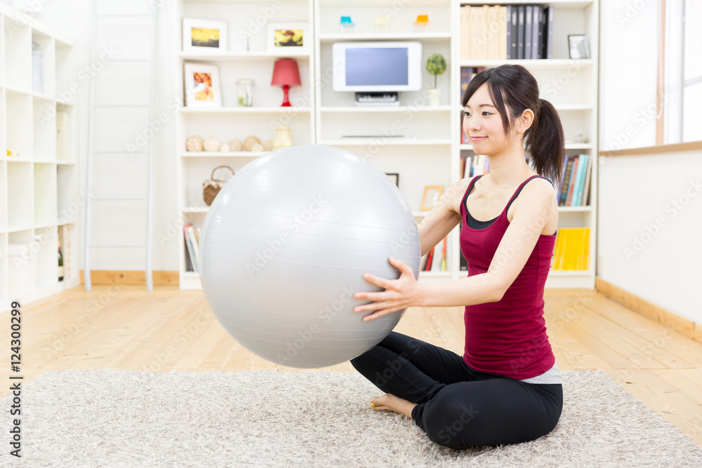 运动型亚洲女性在客厅使用平衡球