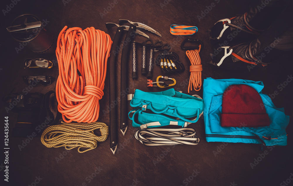 攀登装备套装：橙色绳索、冰爪、冰斧、鞋子、挽具和其他套装，位于黑暗的背景上