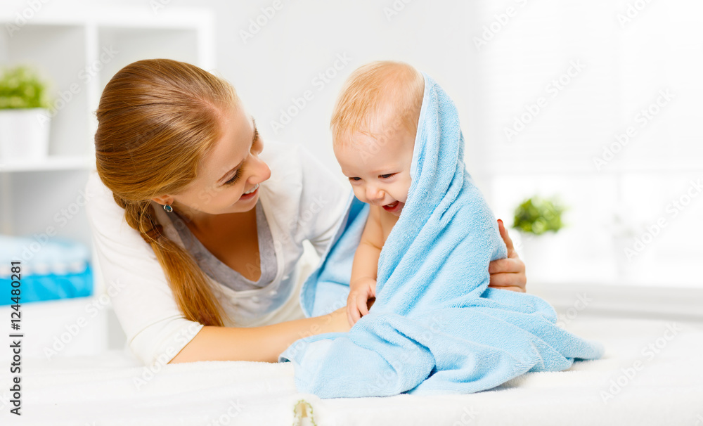 快乐的家庭母亲和婴儿沐浴后用蓝色毛巾