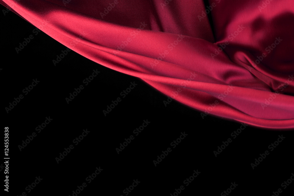 红色织物在风中流动，织物在运动中波动。隔离在黑色背景上
