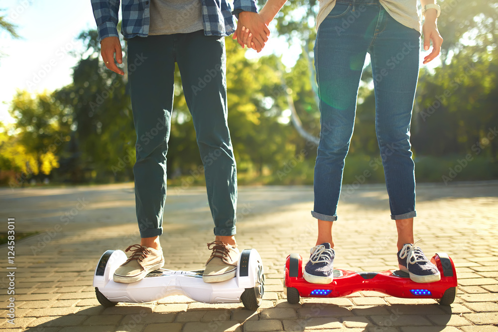 young man and woman riding on the Hoverboard in the park. content technologies. a new movement. Clos
