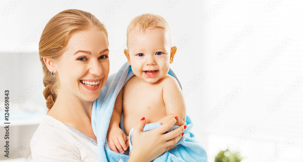快乐的家庭母亲和婴儿沐浴后用蓝色毛巾