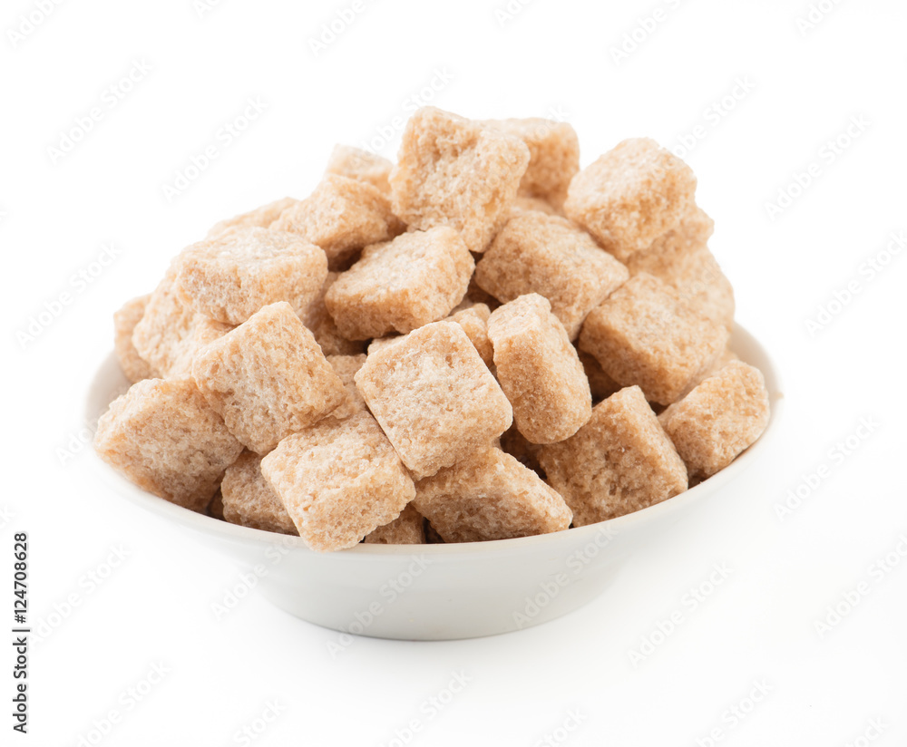 Pieces of brown cane sugar in white bowl isolated.