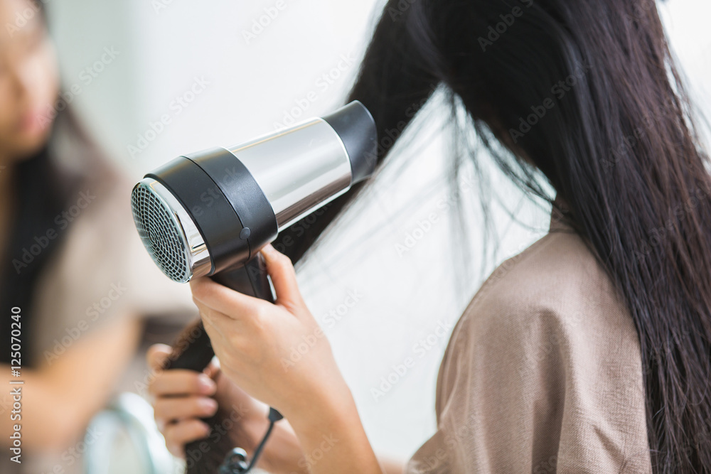 女人用吹风机加热头发。