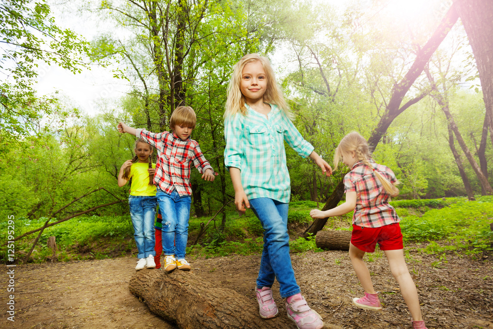 快乐的孩子们在原木上行走，在森林中保持平衡