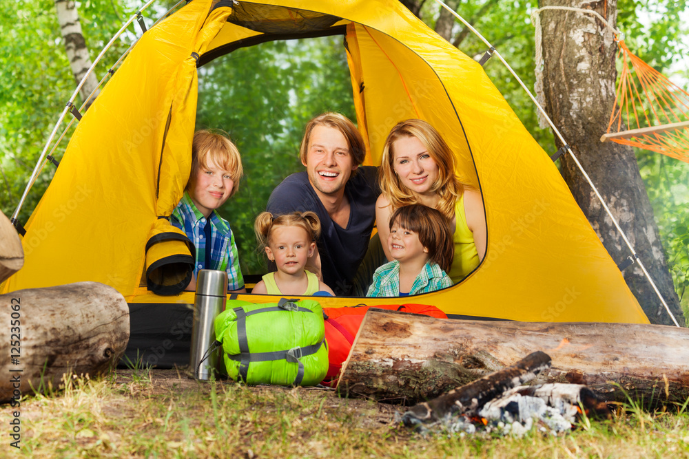 快乐的年轻家庭在树林里的帐篷里放松