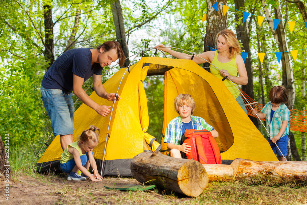 幸福的一家人一起在树林里搭帐篷