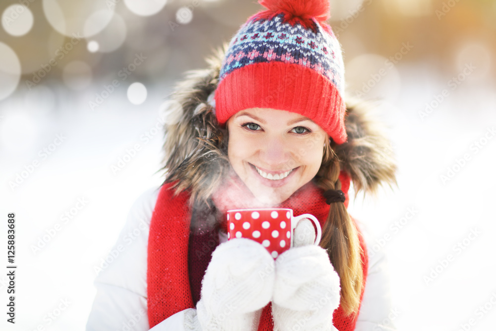 快乐的年轻女人在冬天散步时喝一杯热茶