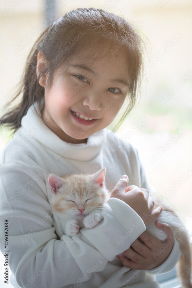 快乐的亚洲小女孩拥抱可爱的苏格兰折叠小猫