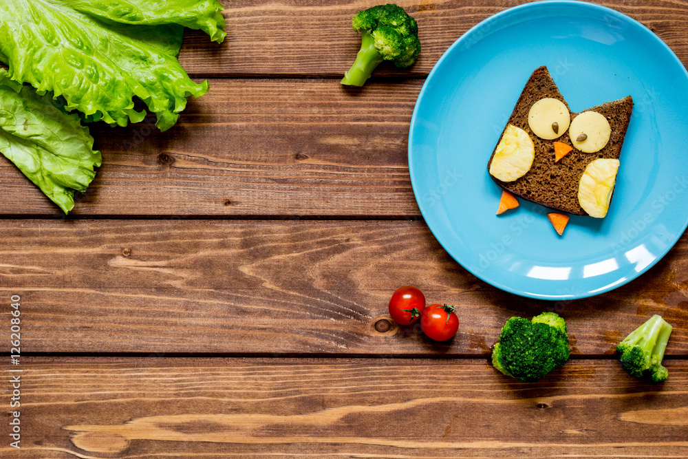 蓝色盘子上的儿童早餐猫头鹰形状三明治俯视图