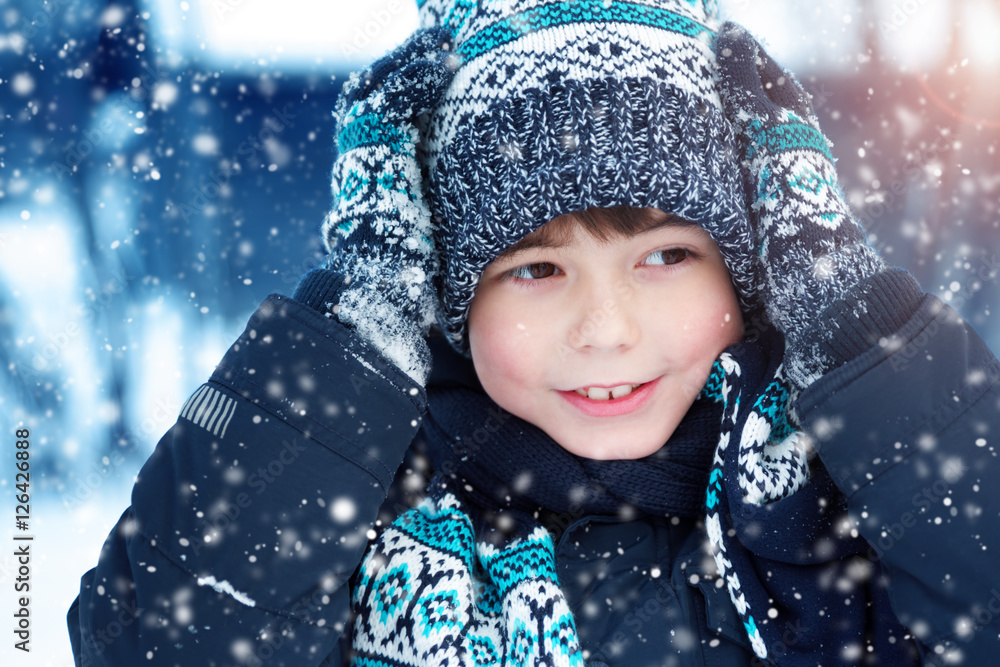 下雪时，男孩在户外戴着针织帽、手套和围巾。孩子穿着冬装
