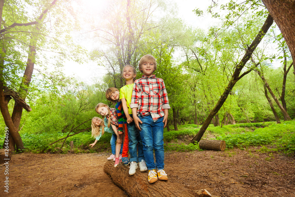 Cute kids standing on a log in the forest