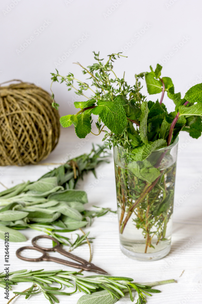 Fresh herbs in glass on wooden background