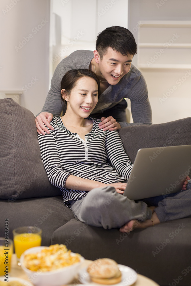 年轻夫妇在客厅沙发上使用笔记本电脑