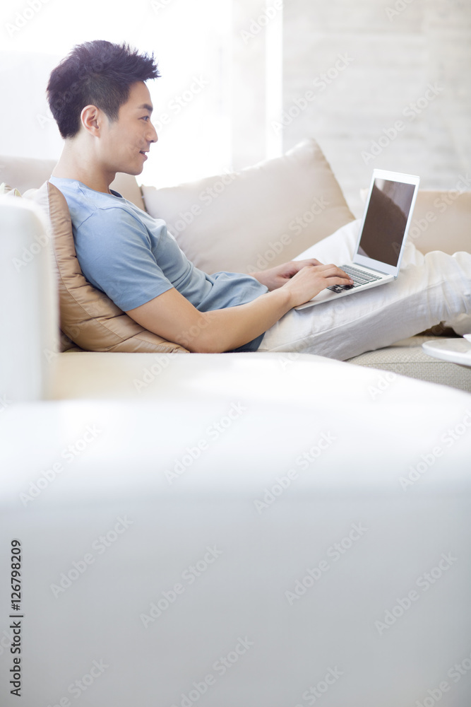 年轻人在沙发上使用笔记本电脑