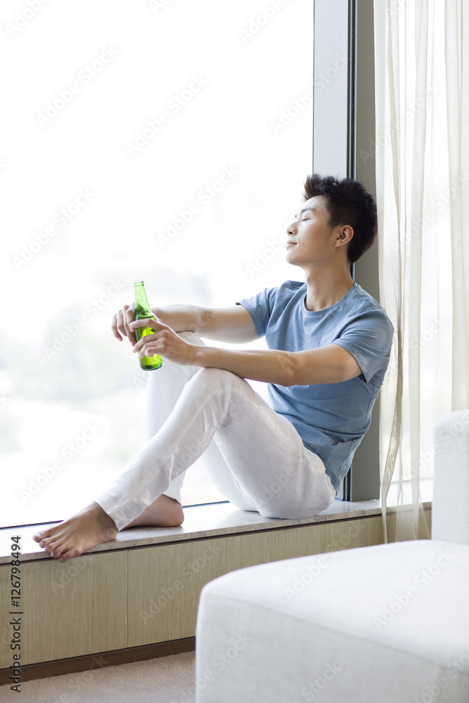 Young man drinking beer at home