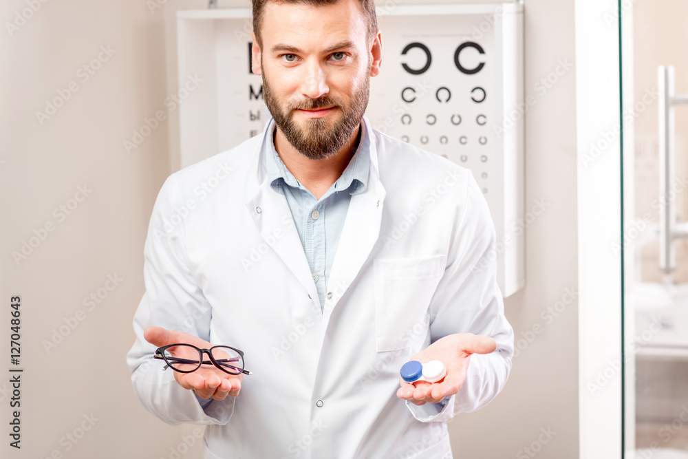 眼科医生站在柜子里的视力表前，在眼镜和镜片之间进行选择