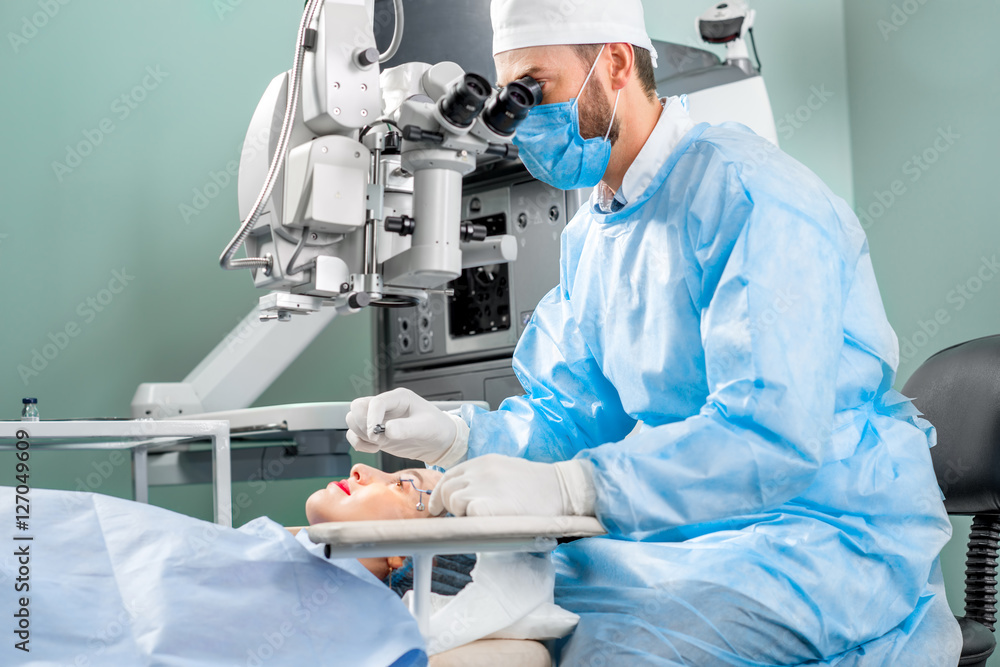 外科医生在手术室使用手术显微镜对女性患者的眼睛进行手术
